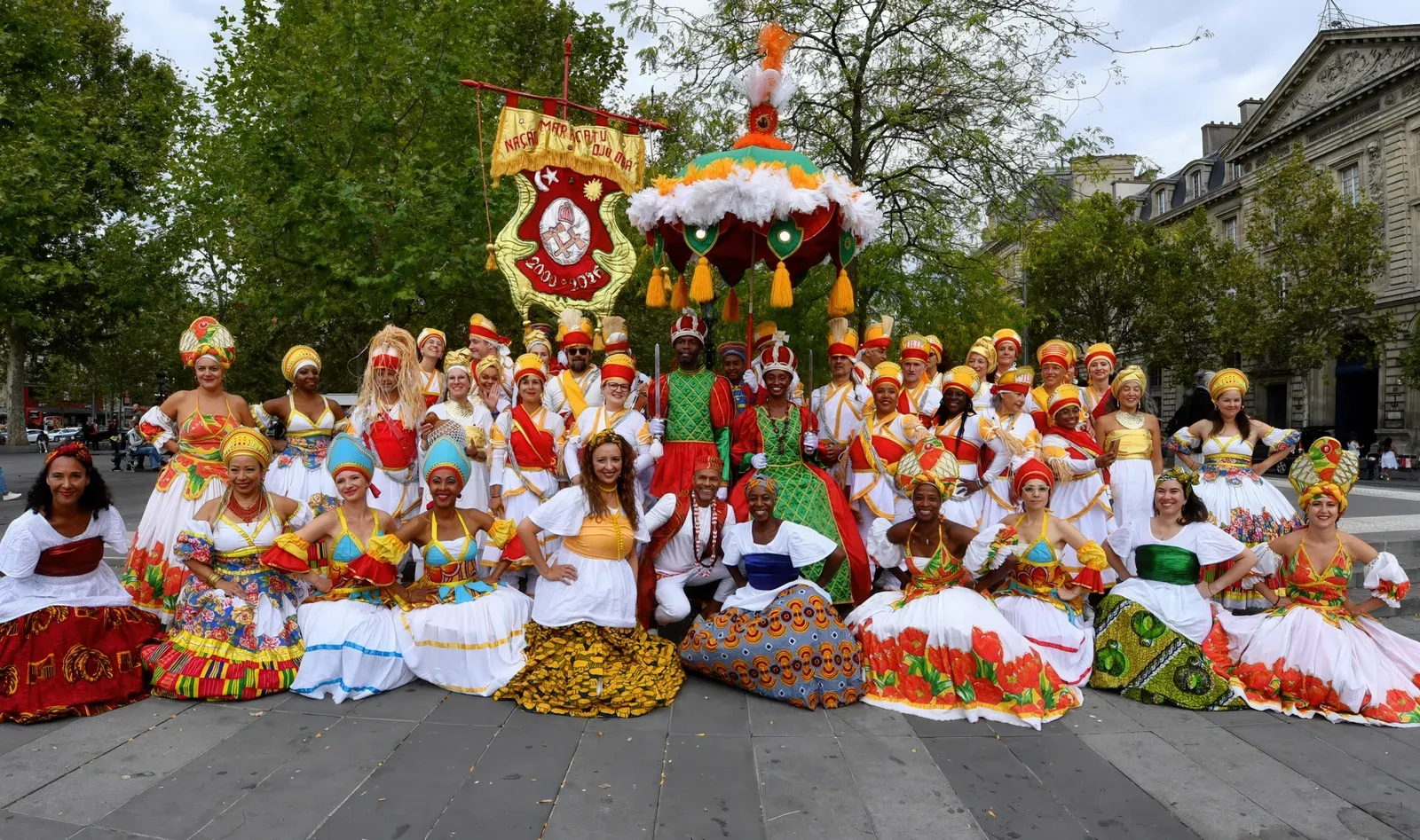 Le groupe Maracatu Ojú Ọba en costumes traditionnels au lavage de la Madeleine 2026, avec sa bannière et son parasol